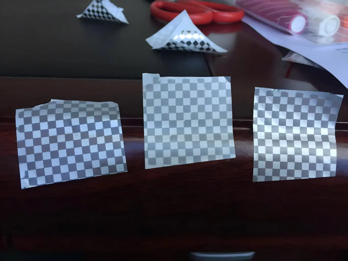 Comparison of early checkerboard tamper-evident material samples used to evaluate transfer consistency and finished surface differences.