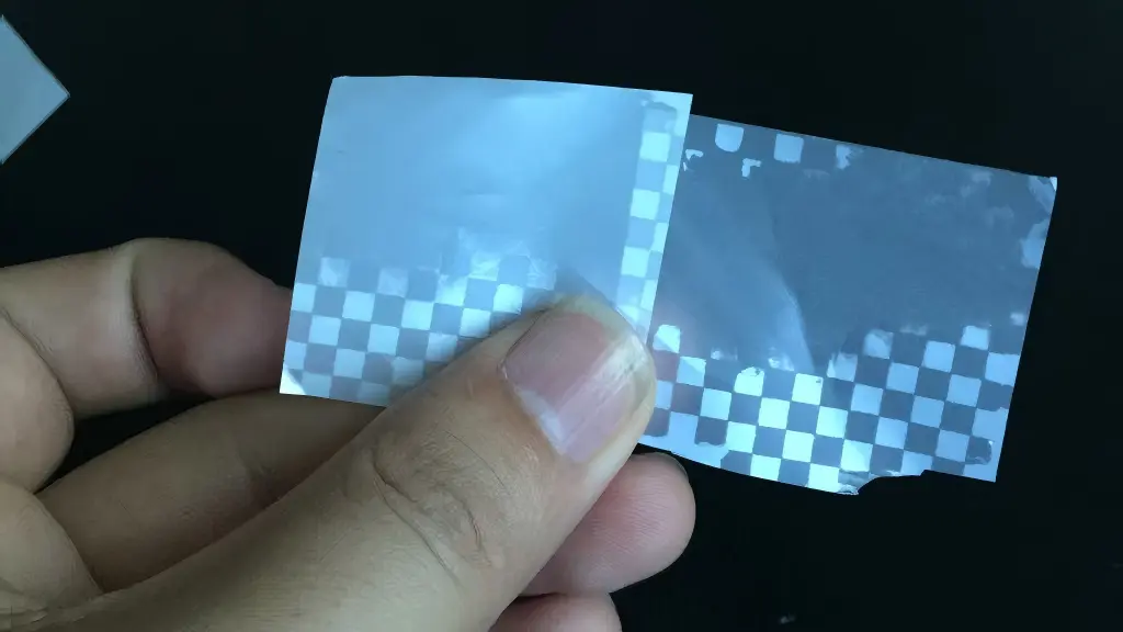 Hand peeling test of matte silver checkerboard tamper-evident material used to evaluate transfer definition and tamper response.